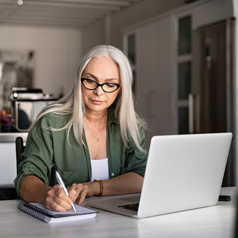 woman with grey hair and glasses focused on task