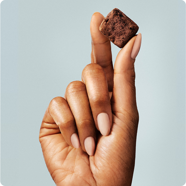 Woman's hands holding a GEM Chocolate Cherry Sleep Essentials nutrient-dense Bite.